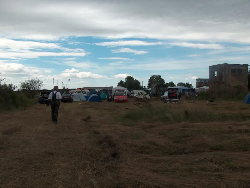 An elderly man walks toward the tents in the distance.