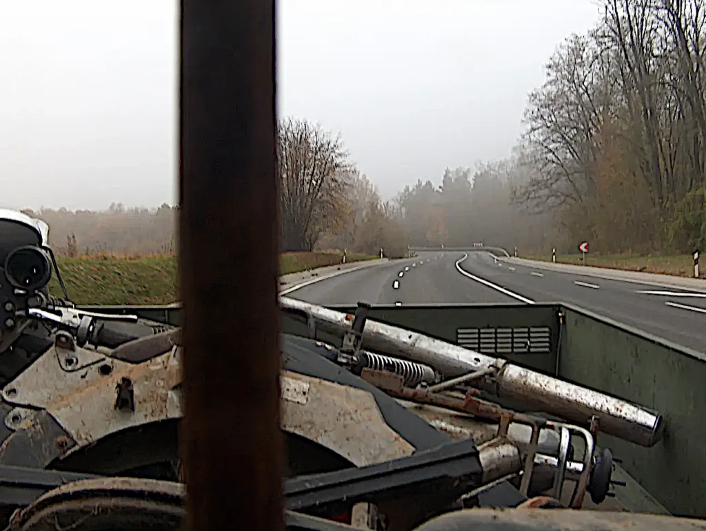 Siklósról hazafelé az úton- a teherautó platója látszik A teherautóból hátrafelé fényképezve a platóra felpakolt motorkerékpár alkatrészek látszanak.