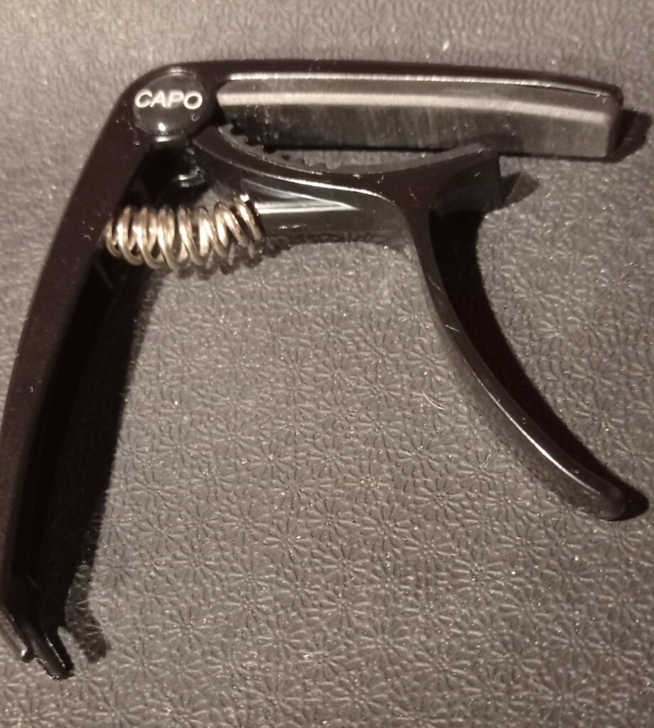 Black guitar capo with spring mechanism, close-up view
