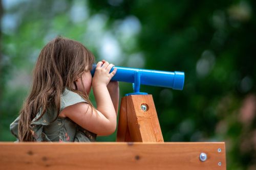 A little girl looking through a blue toy telescope – symbolizing curiosity