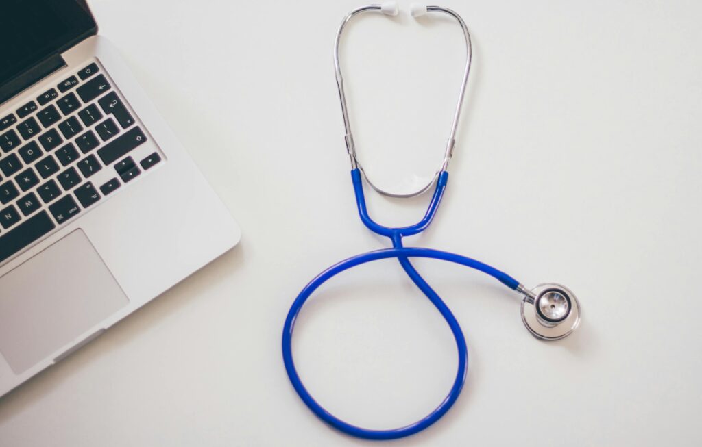 A blue stethoscope next to a laptop – representing my connection to healthcare