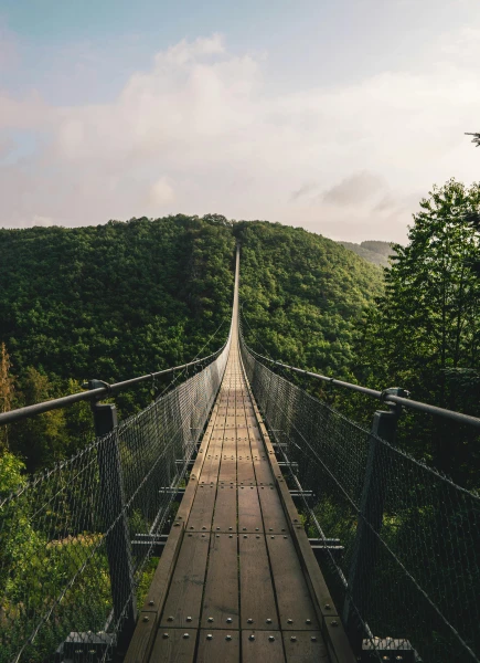 Suspension bridge between green hills – symbol of courage and crossing thresholds