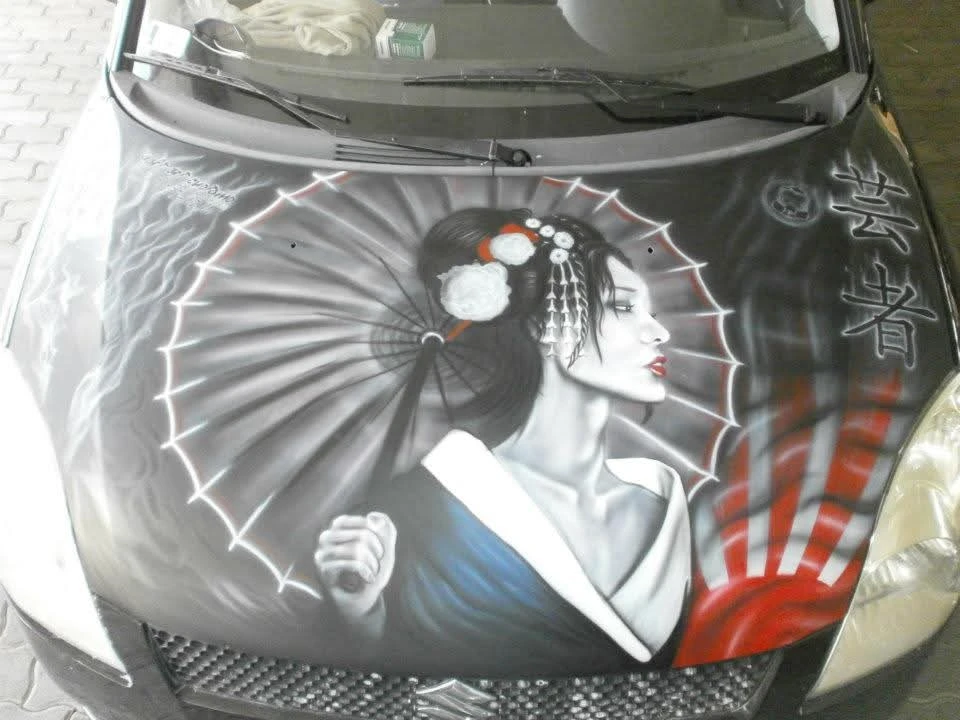 Airbrushed artwork on a car hood showing a traditional geisha with a red and white umbrella and Japanese calligraphy.