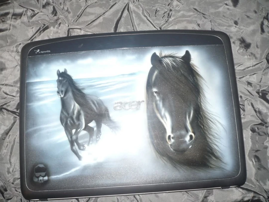 Airbrushed painting on a laptop lid showing a horse galloping through water and a close-up of a horse’s face.