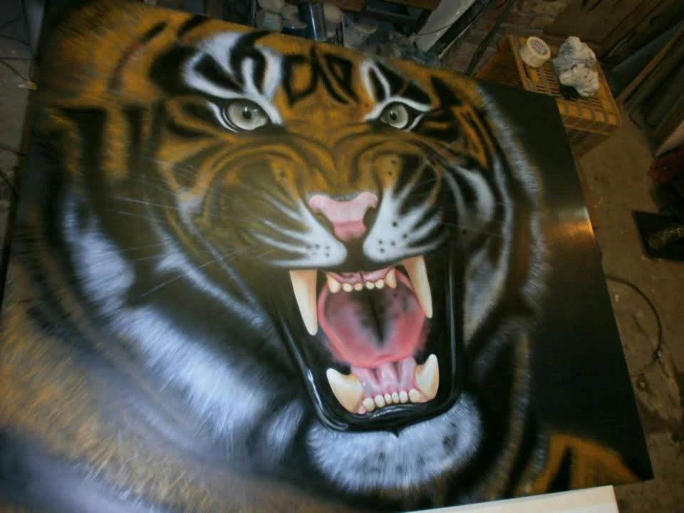 Realistic airbrush painting of a roaring tiger with wide-open mouth and intense eyes on a dark background.