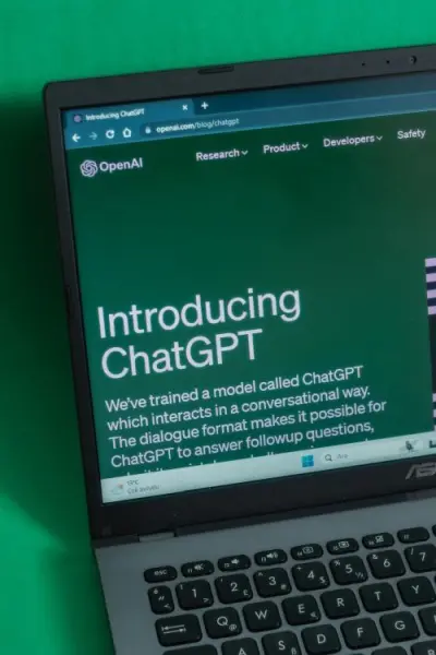 Laptop screen showing ChatGPT introduction page with green background and the headline “Introducing ChatGPT”.