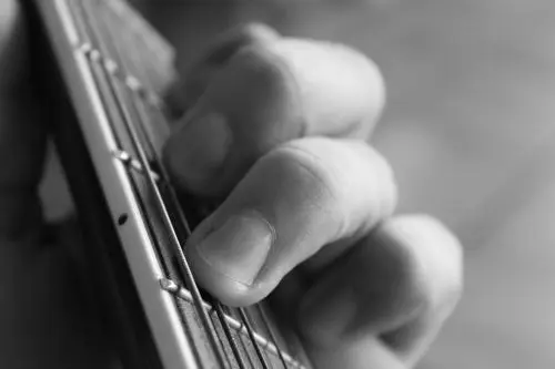 A hand playing the guitar, illustrating finger stretching.