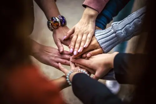 Hands stacked together – symbolizing unity and collaboration within the Vig-Village community