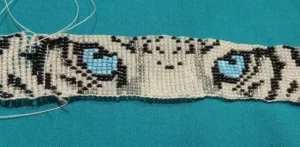 Bead-woven colorful bracelet in unfinished state, shows a white tiger's eyes