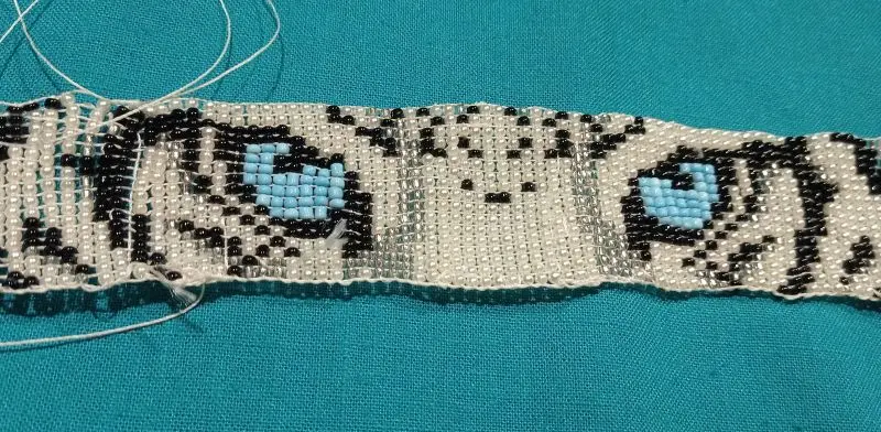 Bead-woven colorful bracelet in unfinished state, shows a white tiger's eyes