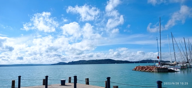 A Balaton látványa a kikötőből. A távolban halványan látszik a tihanyi félsziget dombja, tetején az Apátsággal.