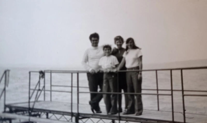 Egy négytagú család áll a mólón, mögöttük a Balaton