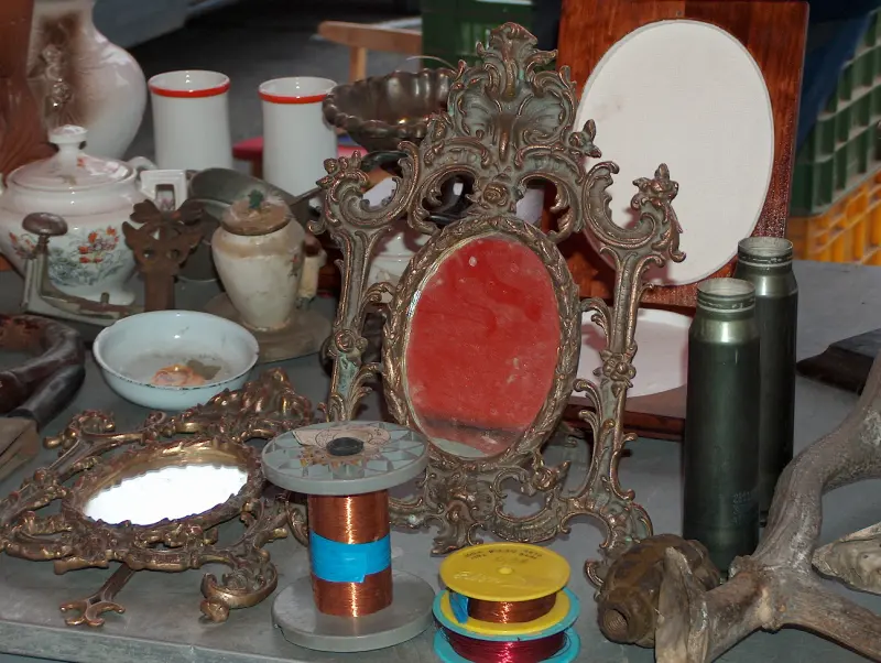 Ornate antique mirror, porcelain bowls and old household objects displayed on a table at the Budaörs Flower Market Fair in October 2005.