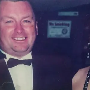 A smiling middle-aged man wearing a suit and bow tie. 