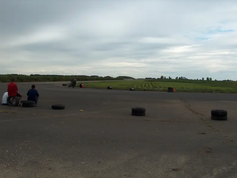 They race on motorcycles on a winding track. Often they are barely visible because they are so far away.