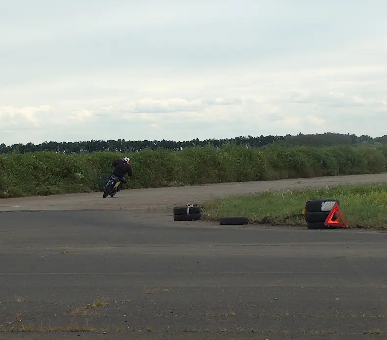 They race on motorcycles on a winding track. Often they are barely visible because they are so far away.