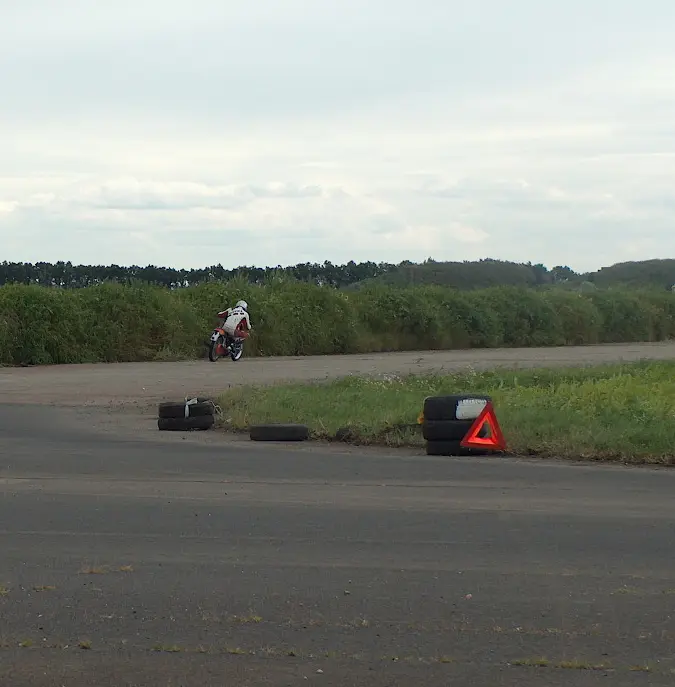 They race on motorcycles on a winding track. Often they are barely visible because they are so far away.