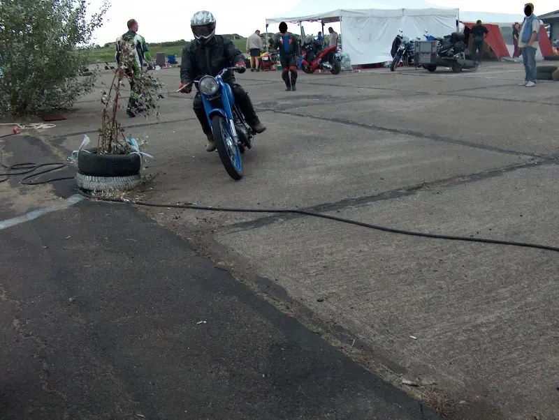 They race on motorcycles on a winding track. Often they are barely visible because they are so far away.