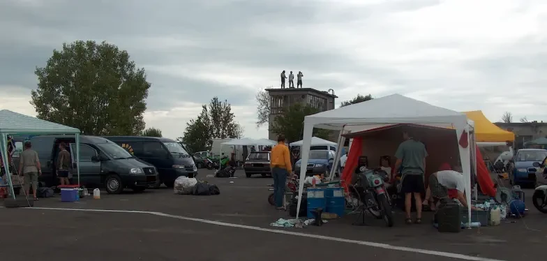 Some people climb onto the roof of a building to watch the distant race events.