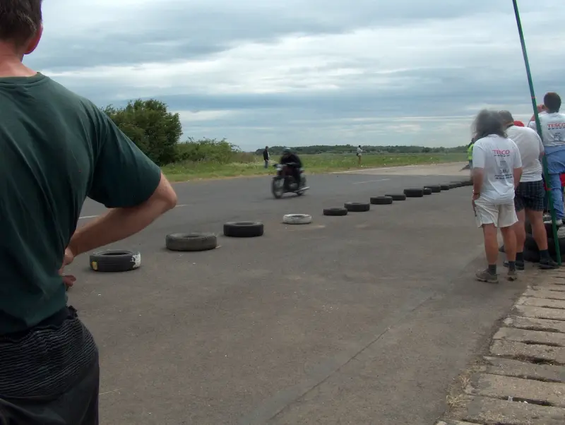 Kunmadarasi 24 órás motorverseny cél vonala. 1 motor már beért. De nem ő volt az első. Közelről, és távolról is emberek fotózzák őt.