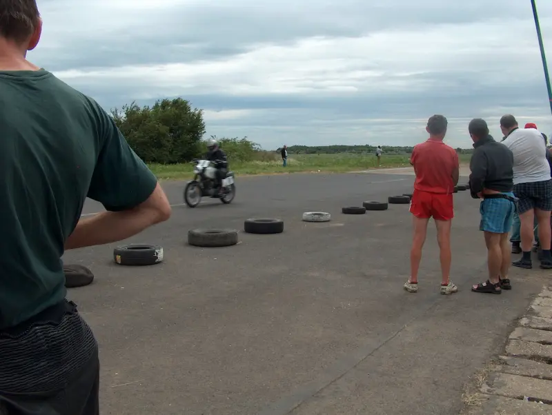 Kunmadarasi 24 órás motorverseny cél vonala. 1 motor már beért. De nem ő volt az első. Közelről, és távolról is emberek fotózzák őt.