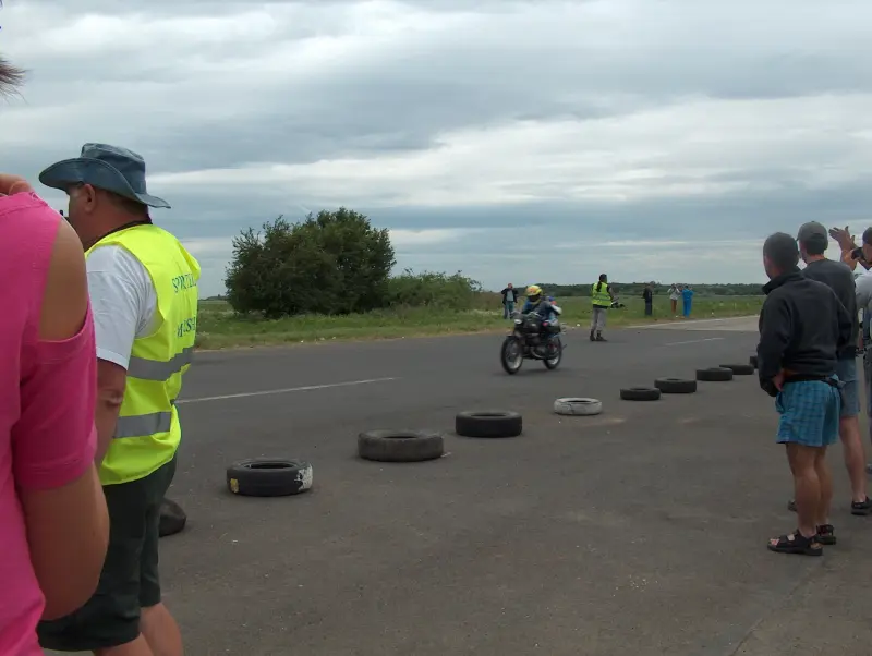 Kunmadarasi 24 órás motorverseny cél vonala. 2 motor már beért. De nem ő volt az első. Közelről, és távolról is emberek fotózzák őt.