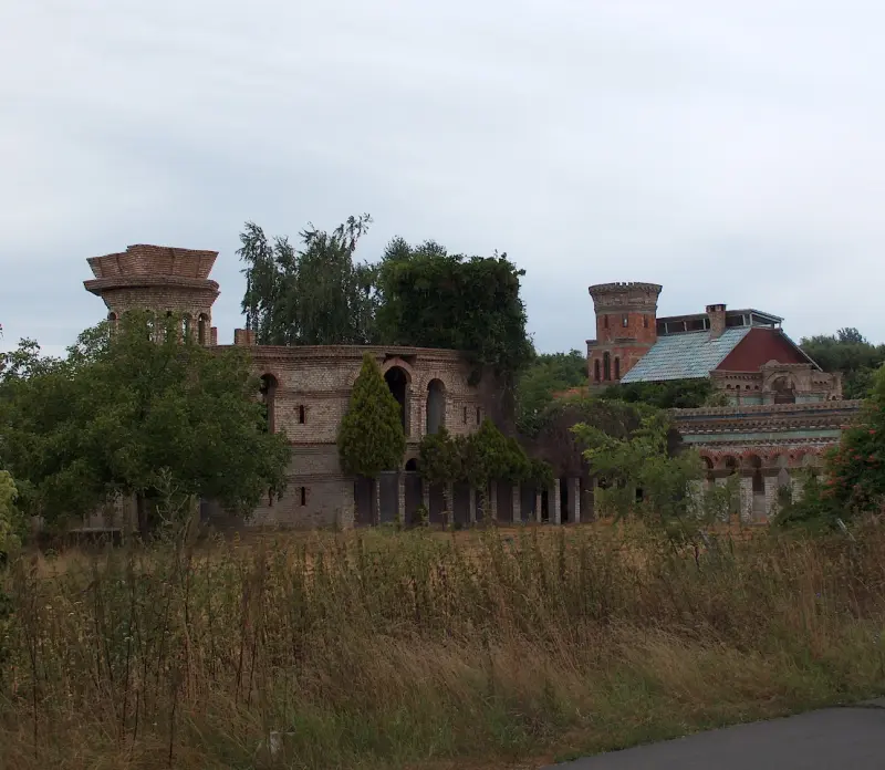 Closer view of the ruined brick building among trees