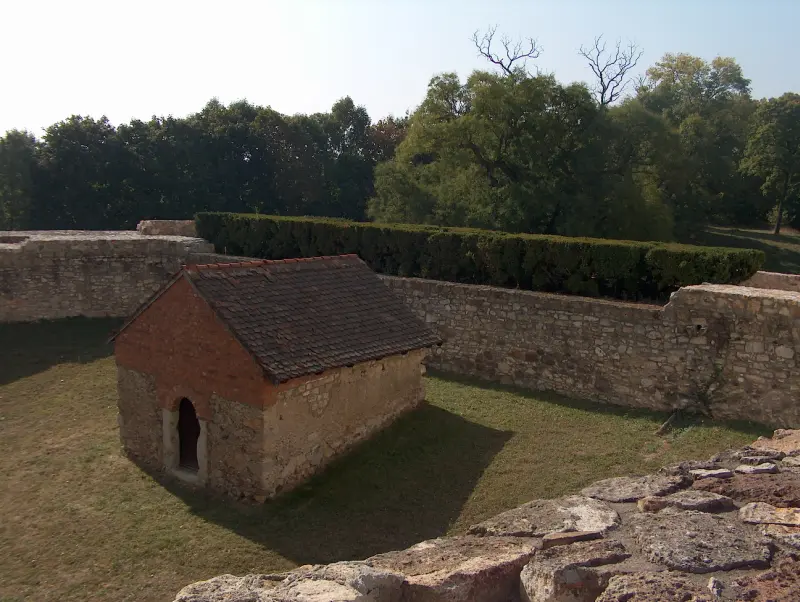 Stone castle walls with a small tiled-roof outbuilding inside Sárospatak Castle.”