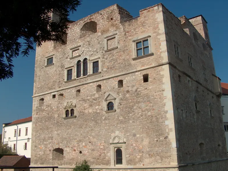 Side view of the massive stone residential tower of the Rákóczi Castle in Sárospatak, featuring medieval Renaissance windows and a simple façade.