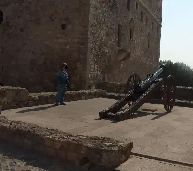 Cannon on display in the courtyard of Sárospatak Castle with the massive stone wall behind.