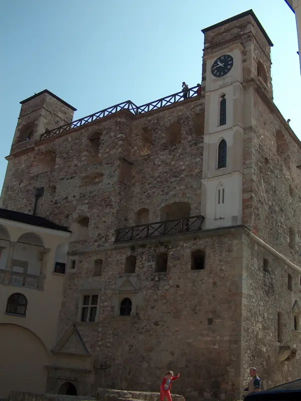 Stone residential tower of Rákóczi Castle with a white clock tower on the right.
