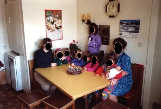 Two adults and several 3-4 year old children are sitting around the table.
