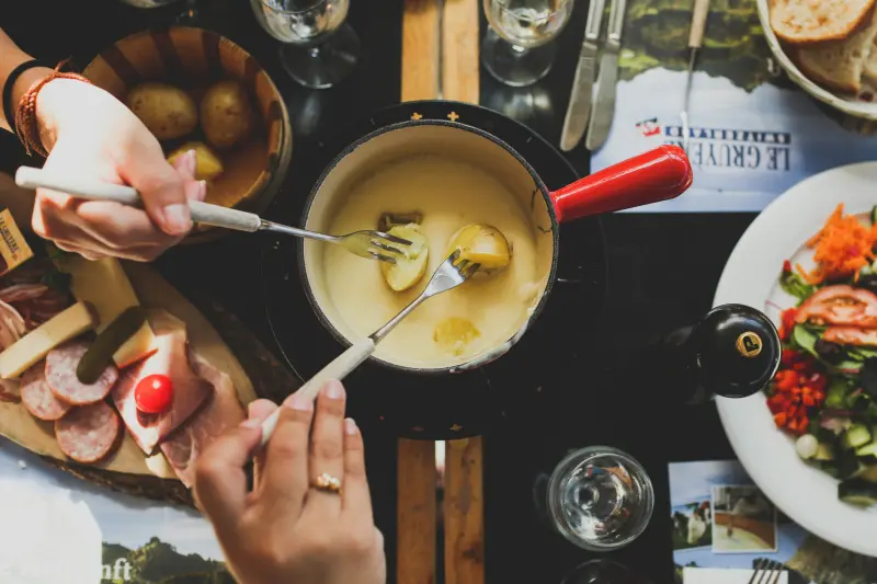 Fondue-be villával mártogató két kéz