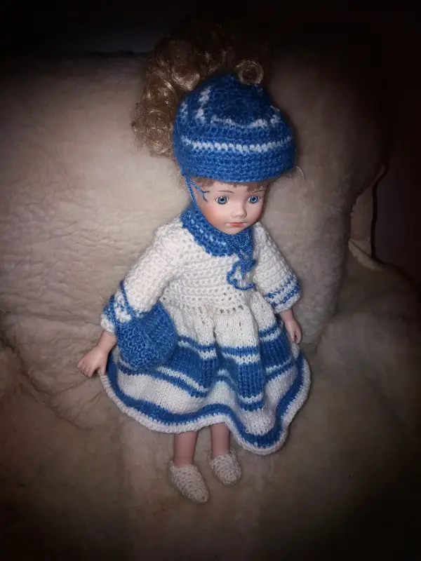 Doll in a white and blue knitted dress, shoes. With a hat and bag.